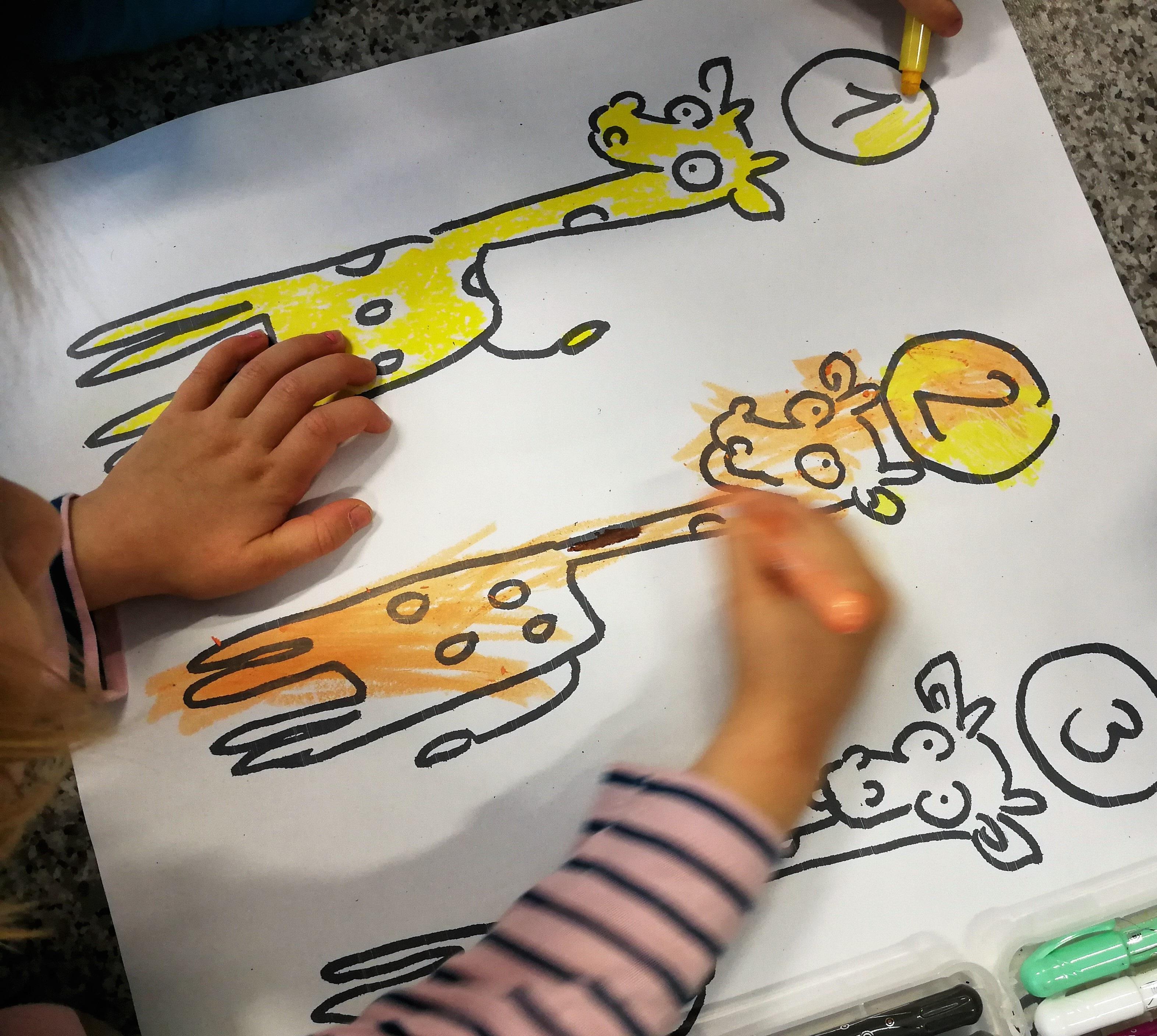 Kuva on Pesäpuun Kirahvityö – Leikki-ikäiset 3–5-vuotiaat -verkkosivulta. Kuvassa lapsi värittää kirahvin kuvia värityskirjasta.